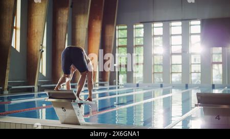 Muscular Mature male Swimmer in piedi su un blocco di partenza e Prepairing per saltare in piscina. Allenamento di atleta professionista sano per il campionato. Sparato con Sunflare Foto Stock