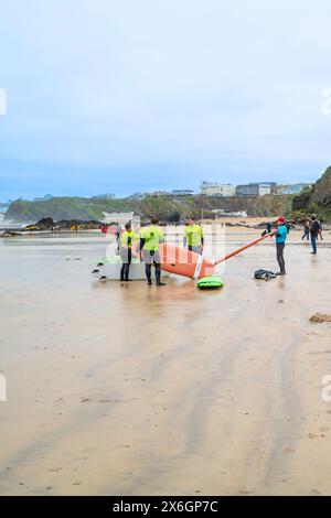 Un istruttore di surf della Escape Surf School che cammina con un gruppo di surfisti principianti sulla spiaggia di Towan a Newquay, in Cornovaglia, nel Regno Unito. Foto Stock