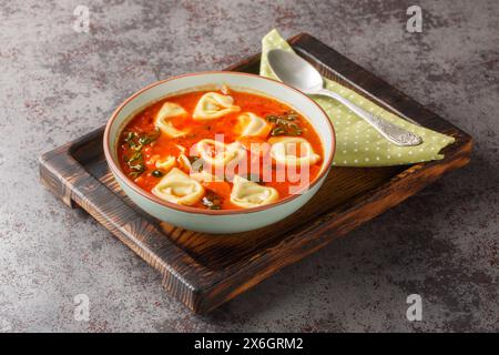 Deliziosa zuppa cremosa di tortellini con spinaci e verdure in primo piano sul piatto del tavolo. Orizzontale Foto Stock