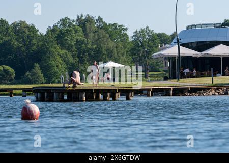 Aluksne, Lettonia - 19 giugno 2021: I giovani saltano in acqua in una soleggiata giornata estiva nel parco, il lago Aluksne Foto Stock