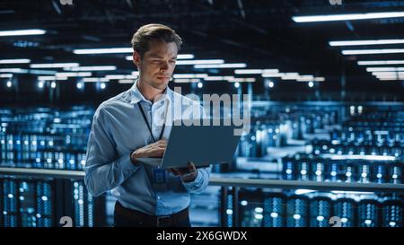 Bellissimo specialista IT SORRIDENTE che utilizza un computer laptop nel data center. Imprenditore di successo e imprenditore di e-business che si affaccia su Server Farm Cloud Computing Facility. Foto Stock