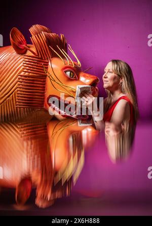 Kat Baxter curatore di archeologia, pulisce una bara a forma di leone (riflessa in un armadietto di vetro) realizzata dal famoso falegname ghanese Paa Joe, noto per la scultura di abebuu adekai, o "proverbi box", che mirano a catturare elementi della vita della persona defunta. La bara fa parte della mostra Living with Death al Leeds City Museum, che esplora i diversi modi in cui le persone sperimentano la morte, la morte e il dolore. Data foto: Mercoledì 15 maggio 2024. Foto Stock