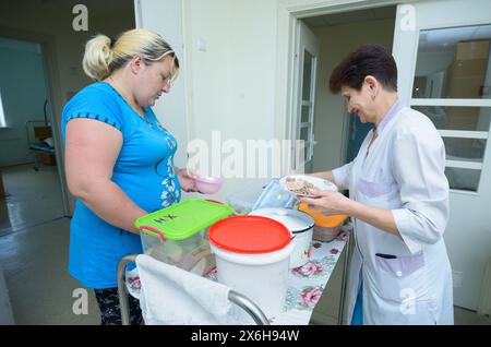 In ospedale. Infermiere in camici da laboratorio che forniscono alle piastre per il paziente il cibo da un carrello per vassoi. 5 giugno 2019. Kiev Centro cittadino di neurochirurgia. Kiev, Ukrain Foto Stock