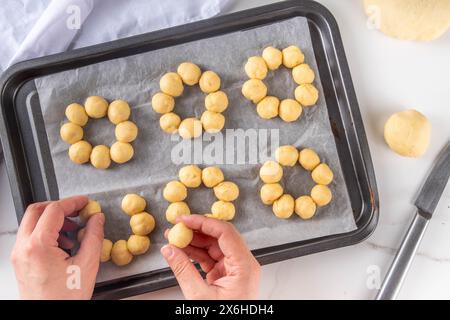 Cucinare preparando ciambelle mochi alla moda. Preparazione fatta in casa di mochi ciambelle dolci, su teglia da forno con le mani della donna in foto, spazio copia con vista dall'alto Foto Stock