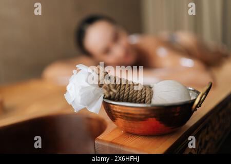 Primo piano selettivo di cialde per massaggio ayurvedico su sfondo sfocato di una cliente donna sdraiata. Primo piano del trattamento ayurvedico Kizhi di Foto Stock