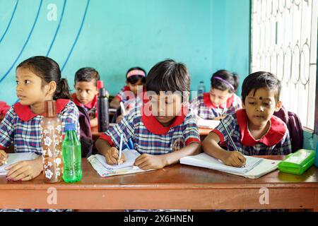 Kolkata, India - 20 ottobre 2024: Bambini in uniforme che prendono appunti e scrivono in una scuola indiana. Concetto di crescita, istruzione, ispirazione e chil Foto Stock