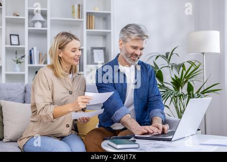 Una coppia matura che gestisce le proprie finanze e i propri documenti lavorando insieme su un notebook a casa. Foto Stock