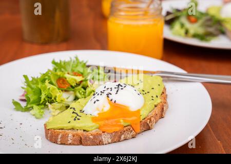 Tosta con crema di avocado e uovo in camicia. Colazione deliziosa. Toast integrale con crema di avocado e focaccine Egg.selective in camicia. Foto Stock