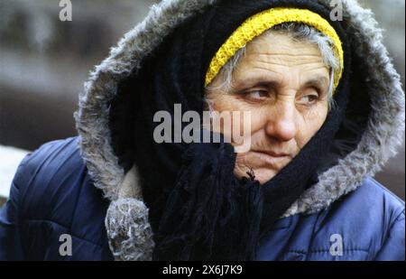 Bucarest, Romania, gennaio 1990. Ritratto di una donna anziana che vende fiori fuori al freddo nel centro di Bucarest. Foto Stock