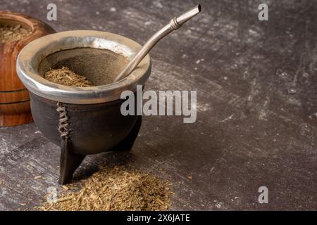 Sana bevanda infusi, classico tè Yerba Mate in una buca con bombilla e erba su sfondo grigio chiaro. Foto Stock