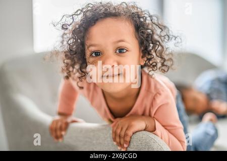 La bambina nera si concentra guardando la tv da sola nel suo salotto. Foto Stock