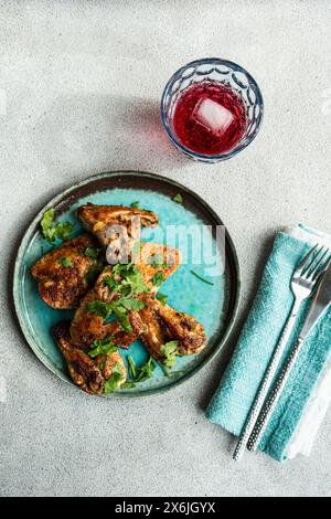Ali di pollo arrosto con coriandolo e un bicchiere di cocktail di ciliegia Foto Stock