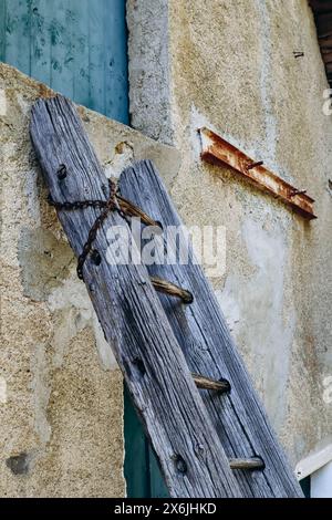 Vecchia scala di legno appoggiata contro il muro della casa Foto Stock