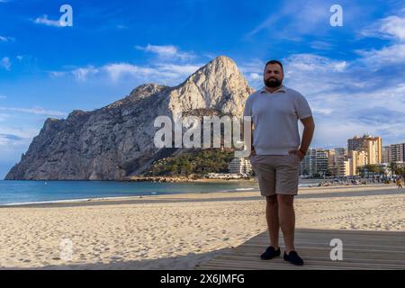 Questo ritratto cattura un uomo di 30 anni mentre si trova in un conforto riflessivo, guardando l'iconica roccia di Ifach a Calpe, in Spagna. Foto Stock