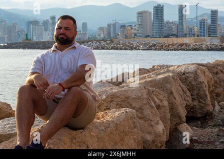 Questo ritratto cattura un uomo di 30 anni seduto sulle coste rocciose di Calpe, in Spagna. Foto Stock