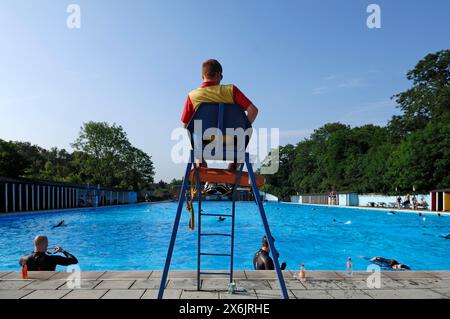 Bagnino in servizio nell'alto posto a sedere presso la grande piscina esterna Tooting Bec Lido (91m x 30m), Tooting Bec Common, Tooting Bec, Londra, Inghilterra Foto Stock