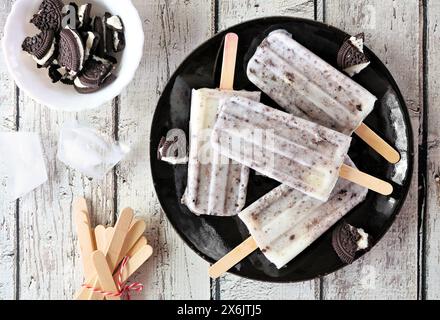 Biscotti e papaveri panna su un piatto nero. Vista dall'alto su sfondo di legno bianco. Foto Stock