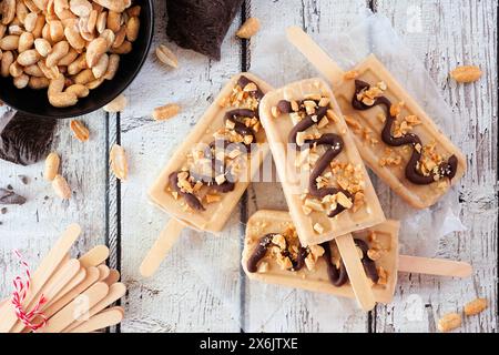 Papaveri al burro di arachidi con gocciolatoio di cioccolato. Sopra la vista della scena della tabella su uno sfondo di legno bianco. Foto Stock