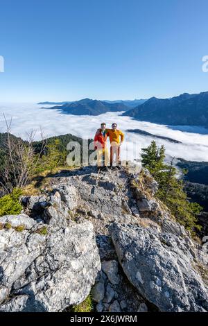 Due amici mettono le braccia l'uno intorno alle spalle dell'altro, gli alpinisti sulla cima rocciosa dell'Ettaler Manndl, la vista sul paesaggio montano e. Foto Stock