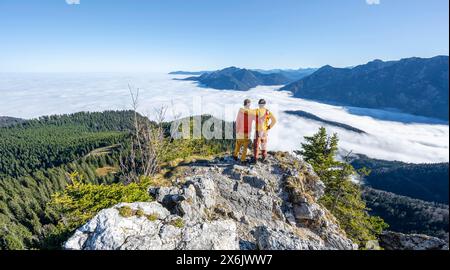 Due amici mettono le braccia l'uno intorno alle spalle dell'altro, gli alpinisti sulla cima rocciosa dell'Ettaler Manndl, la vista sul paesaggio montano e. Foto Stock