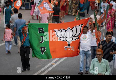 I sostenitori del Bharatiya Janata Party (BJP) detengono una bandiera del BJP mentre arrivano per vedere una roadshow del ministro degli interni dell'Unione Amit Shah, prima della terza fase Foto Stock