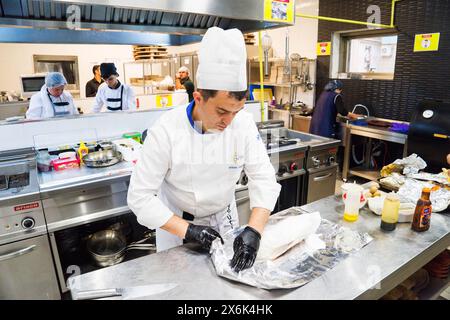 BAKU, AZERBAIGIAN-24 MAY2019 : lo chef prepara anche piatti con gambo di agnello. Il processo di cottura dello chef maschio dello stinco di agnello in una cucina professionale. Cucinare Foto Stock