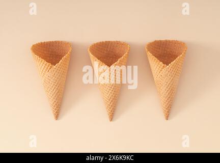 Coni di gelato su sfondo color crema pastello. Concetto creativo estivo. Layout minimalista. Estetica estiva del cibo. Posizione piatta. Foto Stock