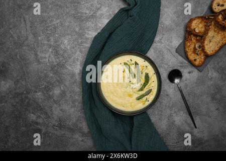 Una ciotola di vellutata zuppa di asparagi bianchi, elegantemente guarnita con vivaci germogli di asparagi verdi Foto Stock