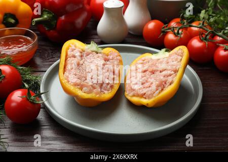 Peperoni ripieni crudi con carne macinata e ingredienti su tavola di legno Foto Stock