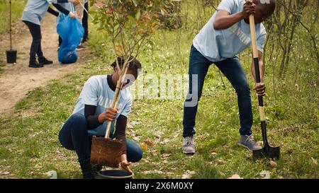 Attivisti ecologici afroamericani piantano piantine in un ambiente forestale, lavorando insieme per preservare e proteggere l'habitat naturale. Progetto Growing Trees. Telecamera A.. Foto Stock