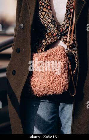 Firenze, Italia - 12 gennaio 2022: Primo piano di una morbida borsa rosa e sciarpa geometrica a motivi geometrici, abbinata a un classico cappotto verde oliva e a un outfit da uomo Foto Stock