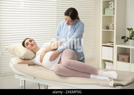 Doula si prende cura di donne incinte al chiuso. Preparazione alla nascita del bambino Foto Stock