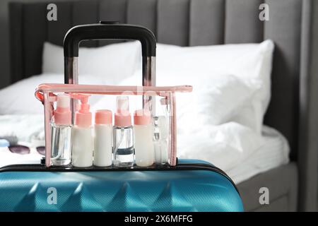 Kit da viaggio cosmetico. Sacchetto di plastica con piccoli contenitori di prodotti per la cura personale su valigia in camera da letto, spazio per testo Foto Stock