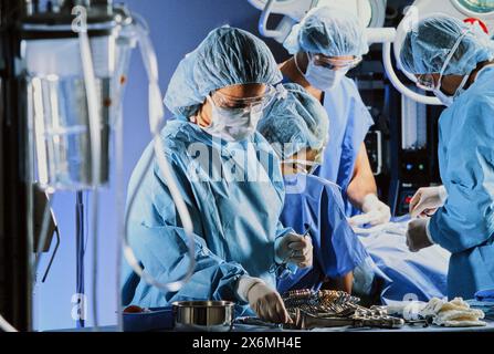 Un gruppo di chirurghi altamente qualificati in scrub e maschere sta lavorando diligentemente in una sala operatoria, eseguendo una complessa procedura chirurgica su una paziente Foto Stock