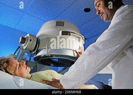 Un medico in abbigliamento medico sta preparando una donna per una procedura diagnostica. Il medico sembra concentrato mentre valuta le condizioni del paziente e il provi Foto Stock