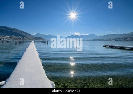 Passerella innevata che conduce al lago Tegernsee, alle montagne del Tegernsee sullo sfondo, a Gmund, Tegernsee, alle Alpi bavaresi, all'alta Baviera, Baviera, G. Foto Stock