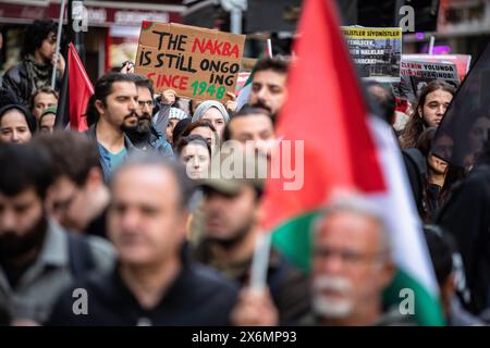 Istanbul, Turchia. 15 maggio 2024. Un manifestante è stato visto portare con sé uno striscione con la scritta "LA NAKBA È ANCORA IN CORSO DAL 1948" durante la marcia. La gente si riunisce per mettere in scena una protesta contro gli attacchi israeliani a Gaza e per commemorare il 76° anniversario della Nakba Day a Istanbul, Turchia. Una protesta commemorativa si è tenuta a Eminonu per celebrare il Nakba Day. I manifestanti si riunirono di fronte al grande ufficio postale (PTT) di Sirkeci e marciarono verso piazza Eminonu. Credito: SOPA Images Limited/Alamy Live News Foto Stock