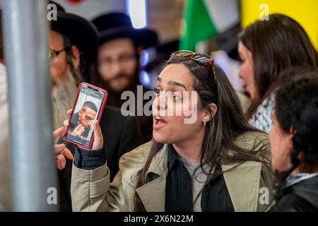 New York, Stati Uniti. 13 maggio 2024. Un contro-manifestante ha l'immagine di un uomo palestinese ferito a un sostenitore filo-israeliano durante la manifestazione dell'Organizzazione sionista d'America a Times Square. Il gruppo ha chiesto di continuare gli attacchi a Gaza e un assalto di terra a Rahfa, dove 1,3 milioni di persone fuggite dai combattimenti in altre parti di Gaza sono state intrappolate contro il confine egiziano con i nostri bisogni umani fondamentali. (Foto di Michael Nigro/Pacific Press) credito: Pacific Press Media Production Corp./Alamy Live News Foto Stock