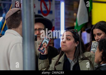 New York, New York, Stati Uniti. 13 maggio 2024. Un contro-manifestante ha l'immagine di un uomo palestinese ferito a un sostenitore filo-israeliano durante la manifestazione dell'Organizzazione sionista d'America a Times Square. Il gruppo ha chiesto di continuare gli attacchi a Gaza e un attacco groundÂ a Rahfa, Â whereÂ 1,3 millionÂ persone fuggite dai combattimenti in altre parti di Gaza sono state intrappolate contro il confine egiziano con i nostri bisogni umani fondamentali. (Credit Image: © Michael Nigro/Pacific Press via ZUMA Press Wire) SOLO PER USO EDITORIALE! Non per USO commerciale! Foto Stock