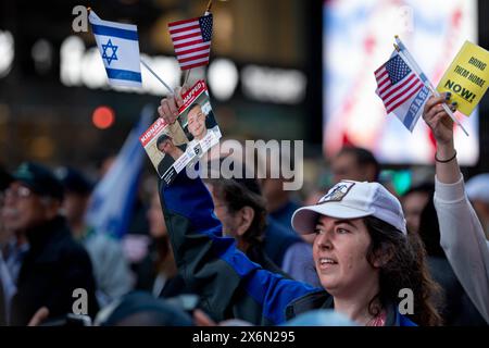 New York, New York, Stati Uniti. 13 maggio 2024. Un sostenitore pro-Israele detiene un volantino rapito e una bandiera durante la manifestazione pro-Israele dell'Organizzazione sionista d'America a Times Square. Il gruppo ha chiesto di continuare gli attacchi a Gaza e un attacco groundÂ a Rahfa, Â whereÂ 1,3 millionÂ persone fuggite dai combattimenti in altre parti di Gaza sono state intrappolate contro il confine egiziano con i nostri bisogni umani fondamentali. (Credit Image: © Michael Nigro/Pacific Press via ZUMA Press Wire) SOLO PER USO EDITORIALE! Non per USO commerciale! Foto Stock