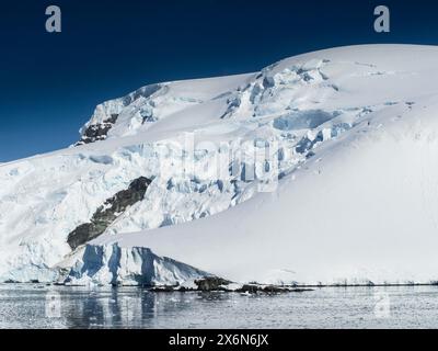 Appeso al ghiacciaio sopra il porto di Mikkelsen, Trinity Island, Arcipelago Palmer, Antartide Foto Stock