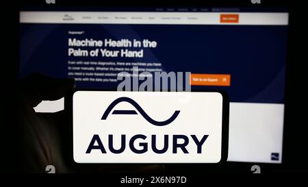 Persona che detiene un cellulare con il logo della società tecnologica israeliana Augury Ltd. Di fronte alla pagina Web aziendale. Mettere a fuoco il display del telefono. Foto Stock