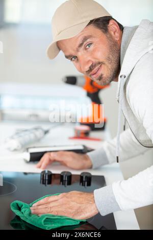 giovane lavoratore che installa un fornello a induzione in cucina Foto Stock