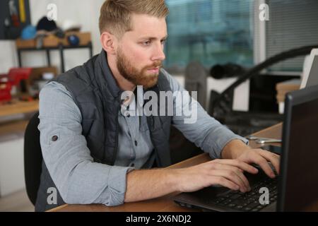 un serio riparatore che lavora in un ufficio Foto Stock