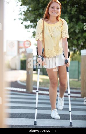 donna disabile con stampelle o bastone da passeggio in strada Foto Stock