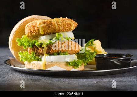 Doppio hamburger di pesce con insalata di patate su un piatto di metallo Foto Stock