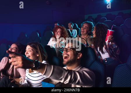 Gruppo di persone allegre che ridono mentre guardano i film al cinema. Foto Stock