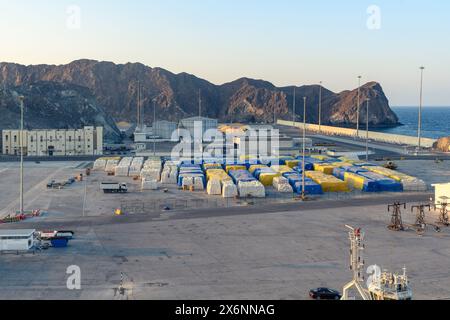 Mascate, Oman - 2 gennaio 2024: Il porto di Mascate è un'immagine dell'attività organizzata al tramonto, che getta una luce dorata sui contenitori Foto Stock