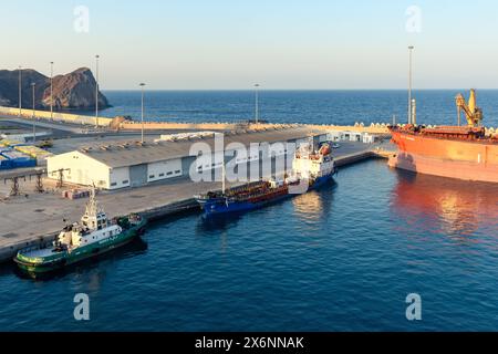Mascate, Oman - 2 gennaio 2024: Il porto di Mascate trasuda un'atmosfera vibrante mentre la luce della sera proietta un caldo bagliore sui vivaci moli. Foto Stock