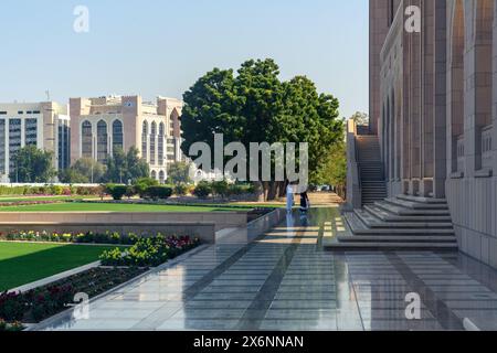 Mascate, Oman - 2 gennaio 2024: Un momento sereno catturato nei giardini vicino alla grande Moschea del Sultano Qaboos. Una persona cammina tra la vegetazione lussureggiante e un Foto Stock